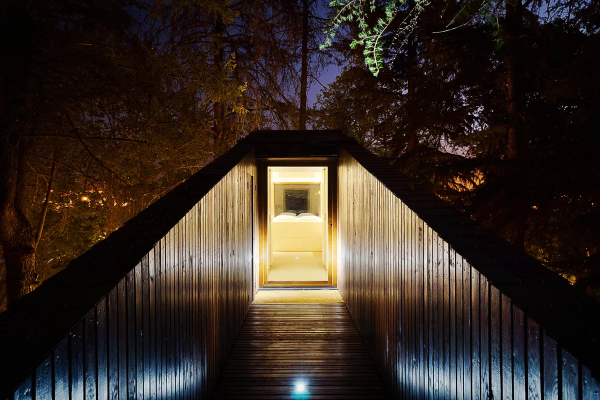 Both dwellings feature a long wooden bridge-like entrance which stretches up from ground level