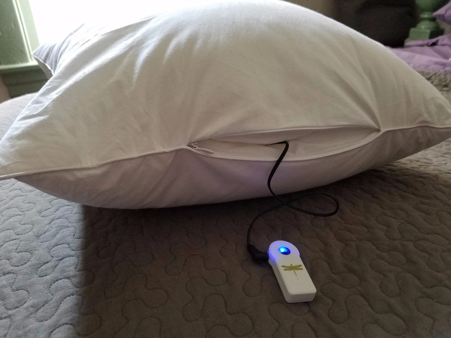 The Dreampad pillow showing the glowing dongle attached the cable that zips up in the side pocket
