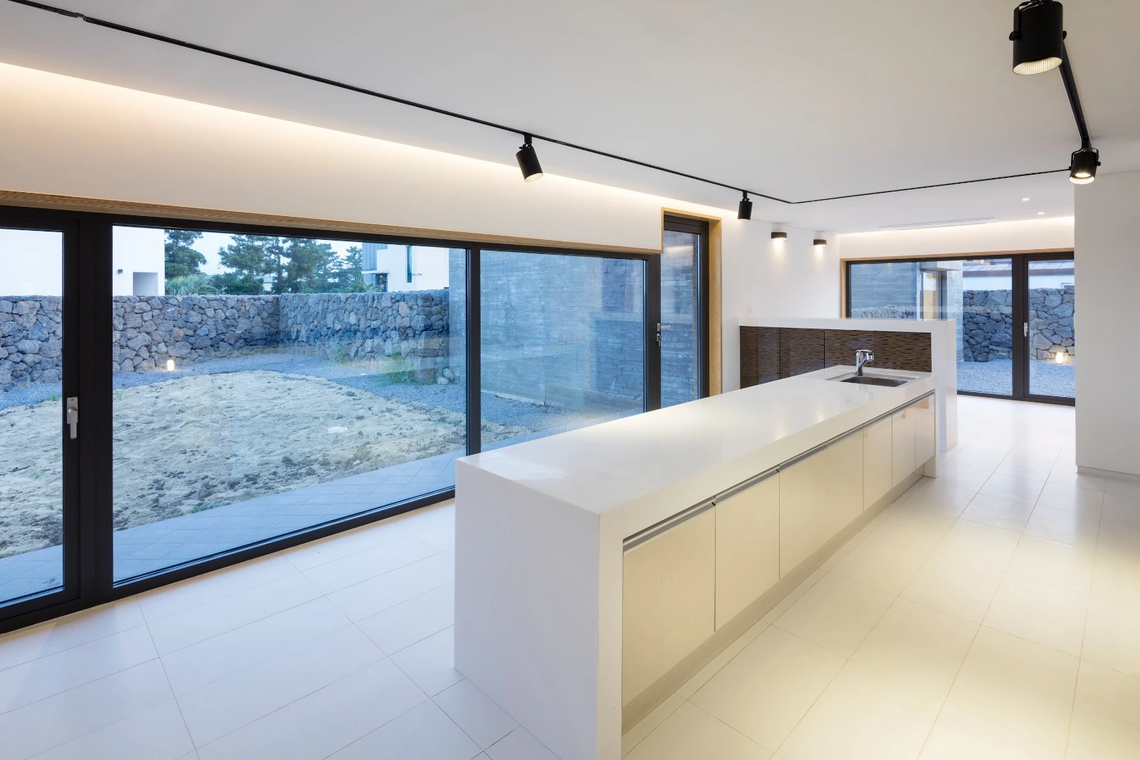 The Wind House project comprises three low-lying holiday homes located on a 644 sq m (6,931 sq ft) plot in the windswept Jeju Island, South Korea