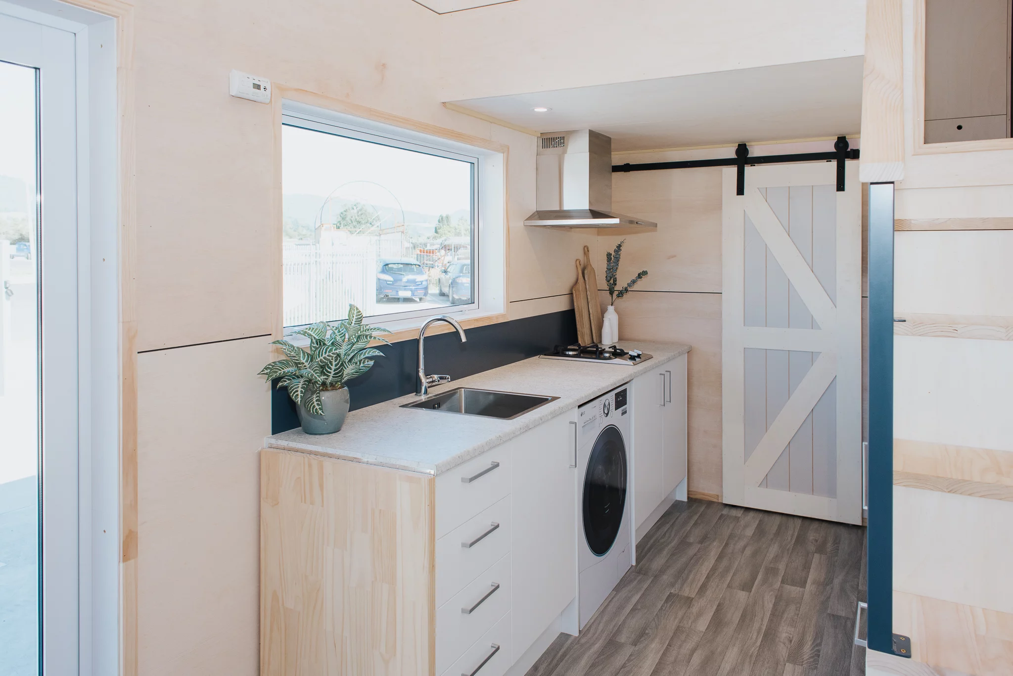 The Purple Palace's kitchen includes a washer/dryer, sink, cabinetry, and a propane-powered two-burner stove