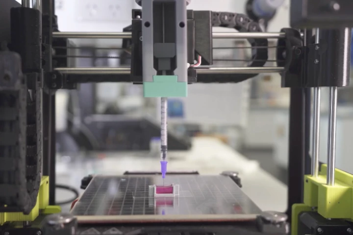 A 3D printer is used to extrude the bio-ink (magenta) into a receptacle simulating a bone cavity