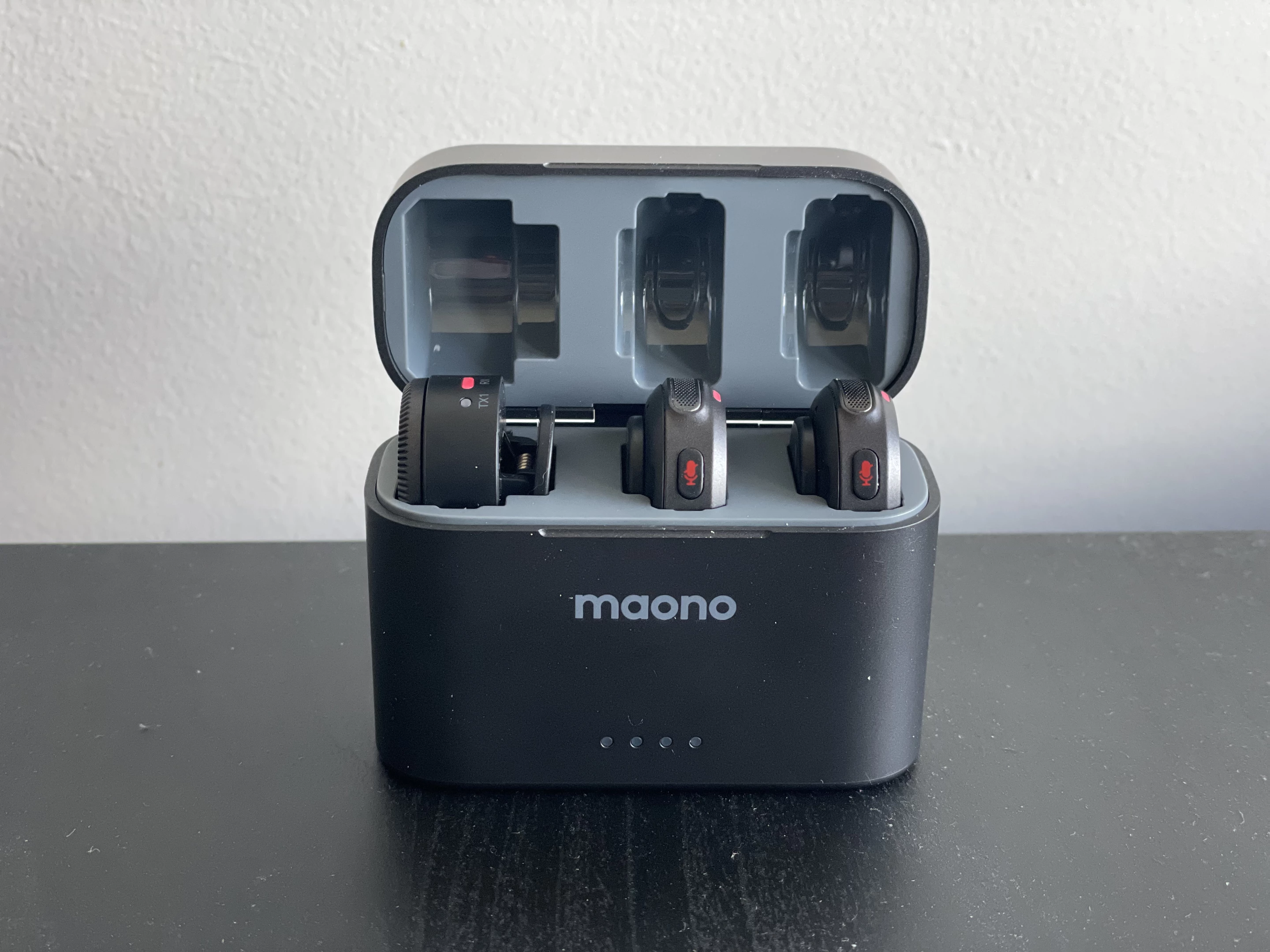 The charging case houses the two microphones and the camera receiver