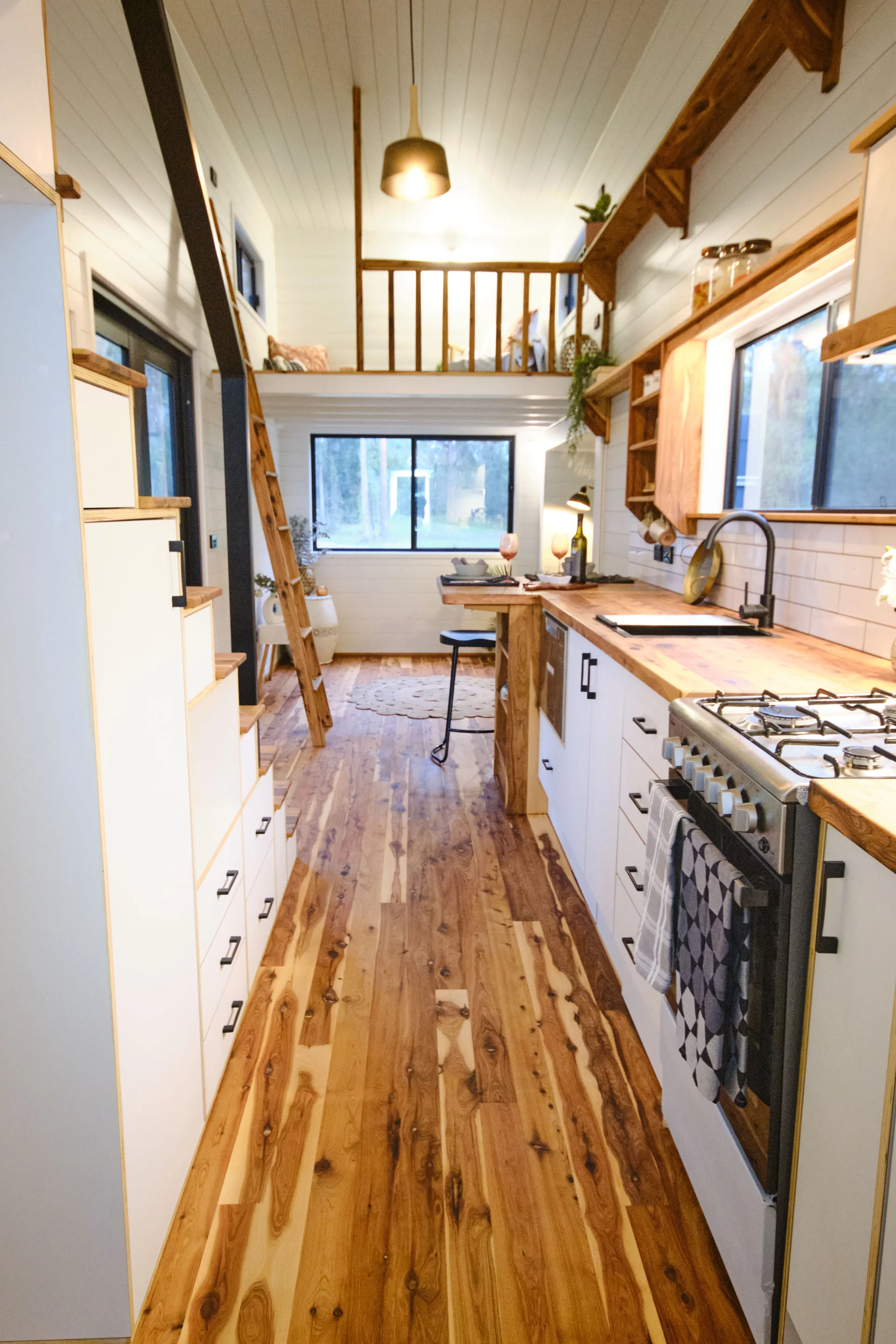 The Grand Sojourner Layout 3's kitchen includes a sink, cabinetry, and an oven with four-burner propane-powered stove