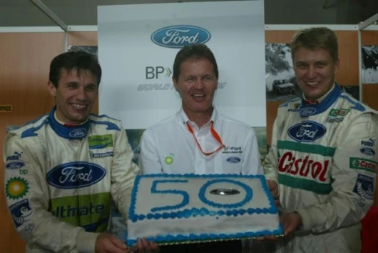 Malcolm Wilson, flanked by drivers Roman Kresta (L) & Toni Gardemeister (R) celebrate Ford's 50th consecutive WRC finish on the 2005 Cyprus Rally. Sunday, 15th May 2005.