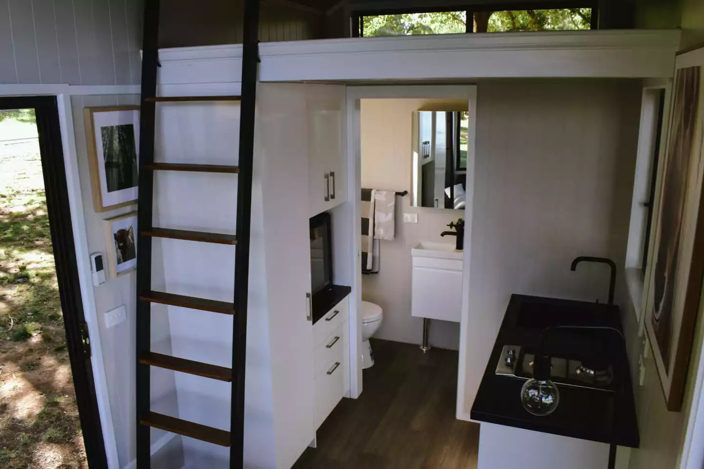 The 4800L Compact's kitchen includes a sink, two-burner propane-powered stove, and a microwave, plus cabinetry