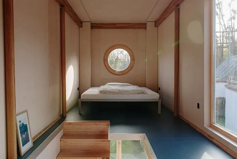 The second floor boasts an expansive bedroom space with porthole window