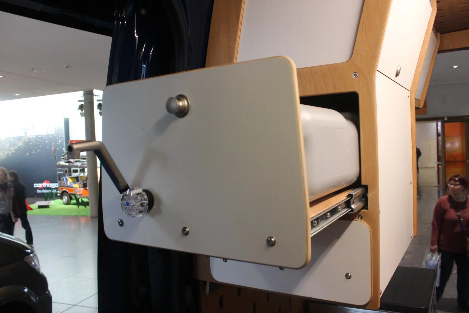 Autocom has designed a very different style of camper van kitchen for its Cargo Camper, a wall-mounted cabinet with fold-out faucet and slide-out stove/wash basin platform