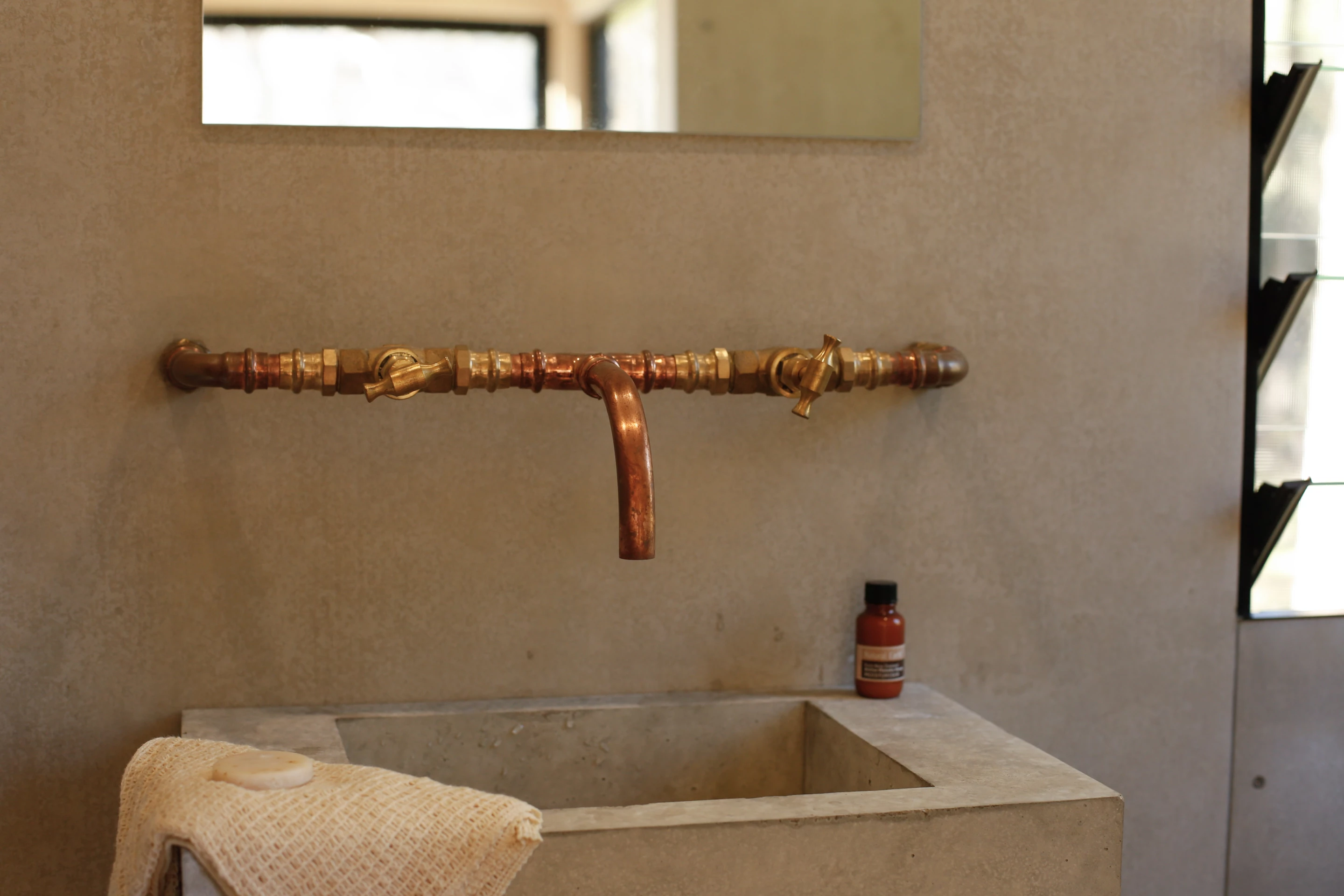 The Barrington Tops Cabin's bathroom features copper pipe taps, accentuating the utilitarian aesthetic of the room