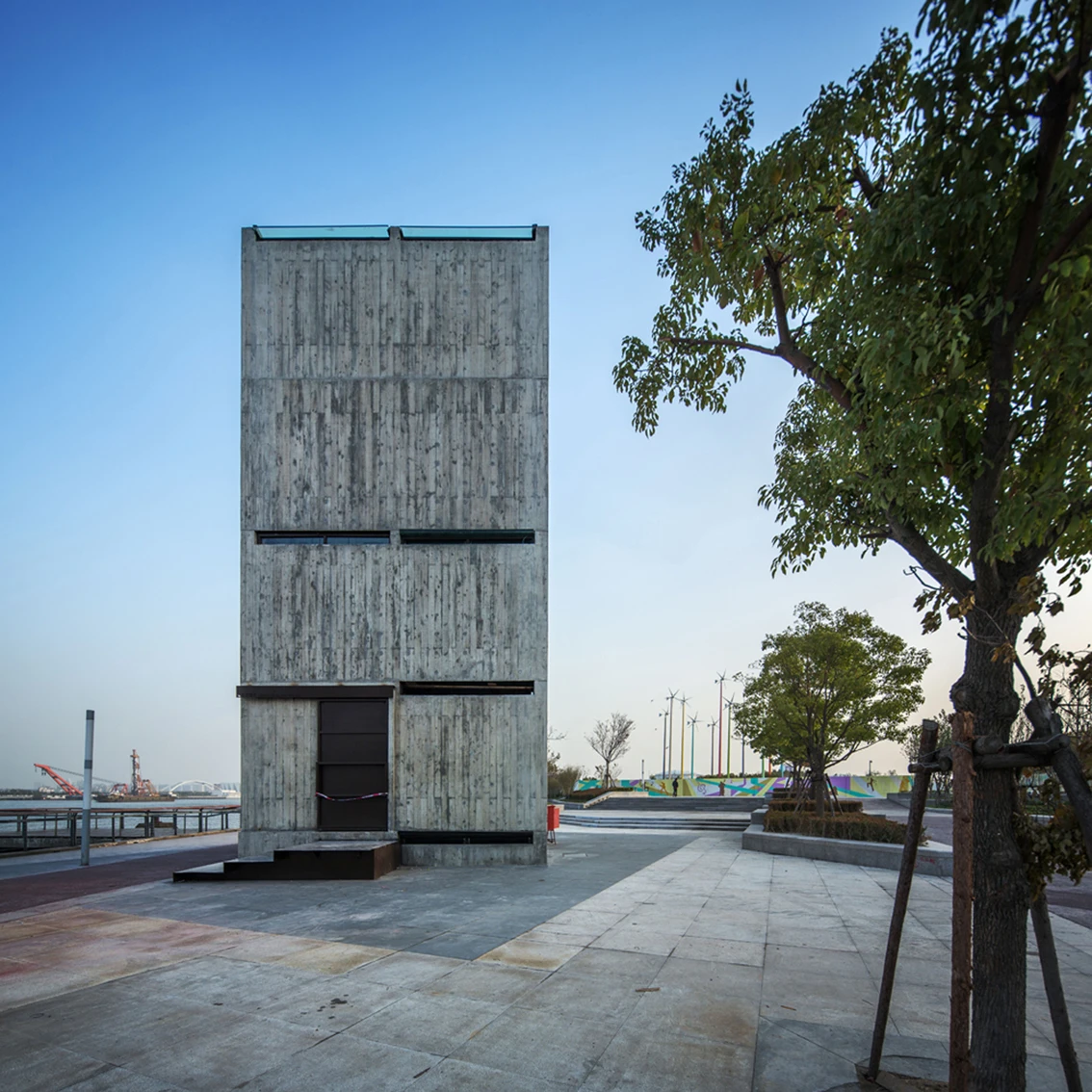 A rough concrete facade is broken only by a few small slits which emit light onto the street outside at night (Photo: Atelier FCJZ)