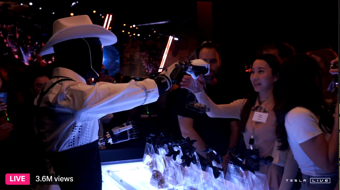 An Optimus in a cowboy hat hands out gift bags to attendees... But only if they beat it at rock paper scissors