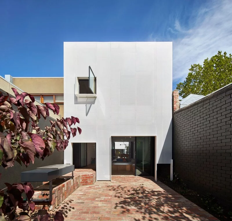 The rear of the home sports a white perforated metal facade to filter the sun's glare