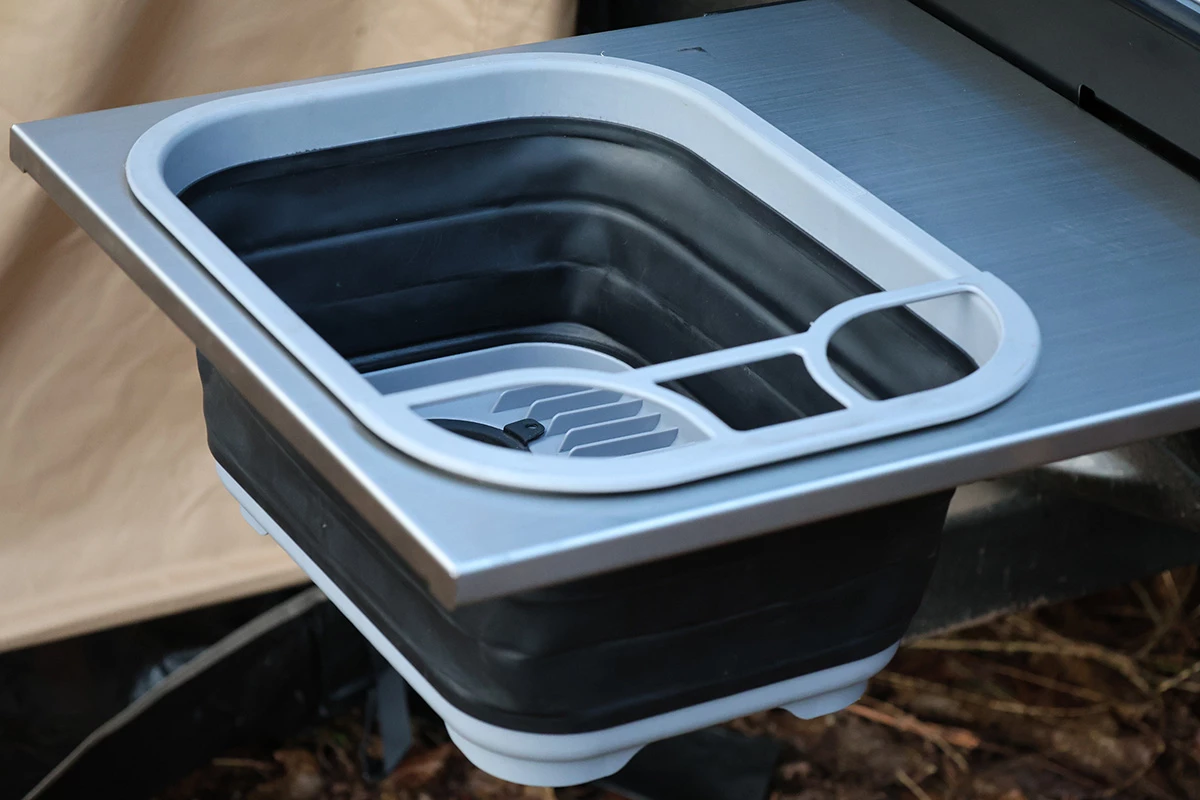 A roller drawer hides away this collapsible sink, as well as a three-burner gas stove