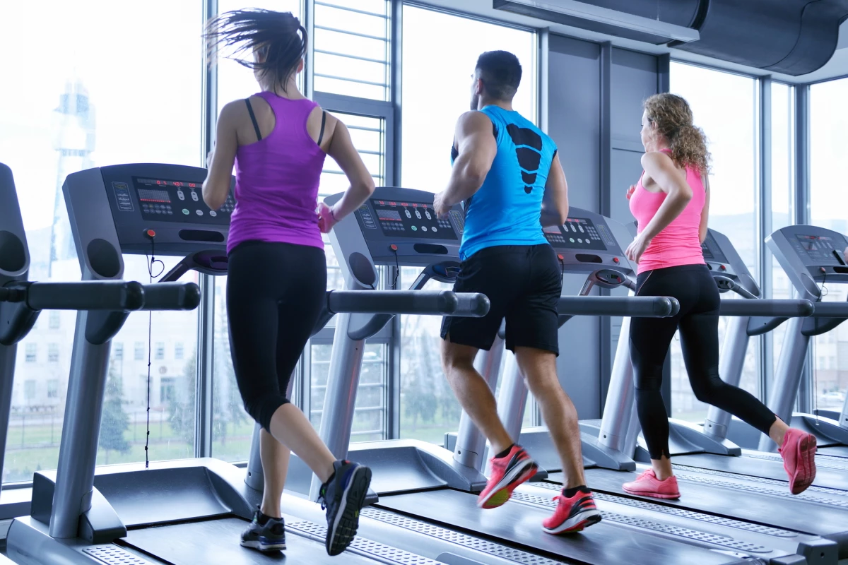 group of young people running on treadmills in modern sport gym