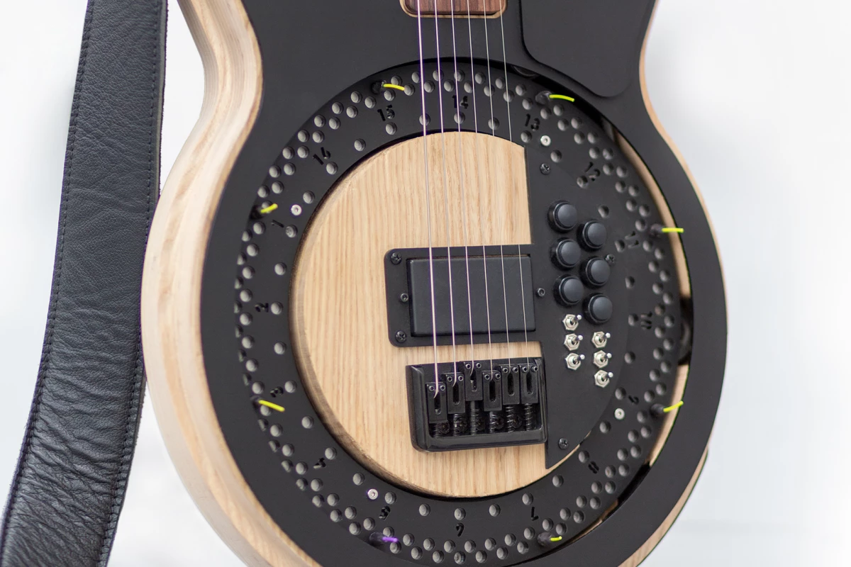The motor-driven disc has guitar picks attached to it, which strike the strings when it spins up