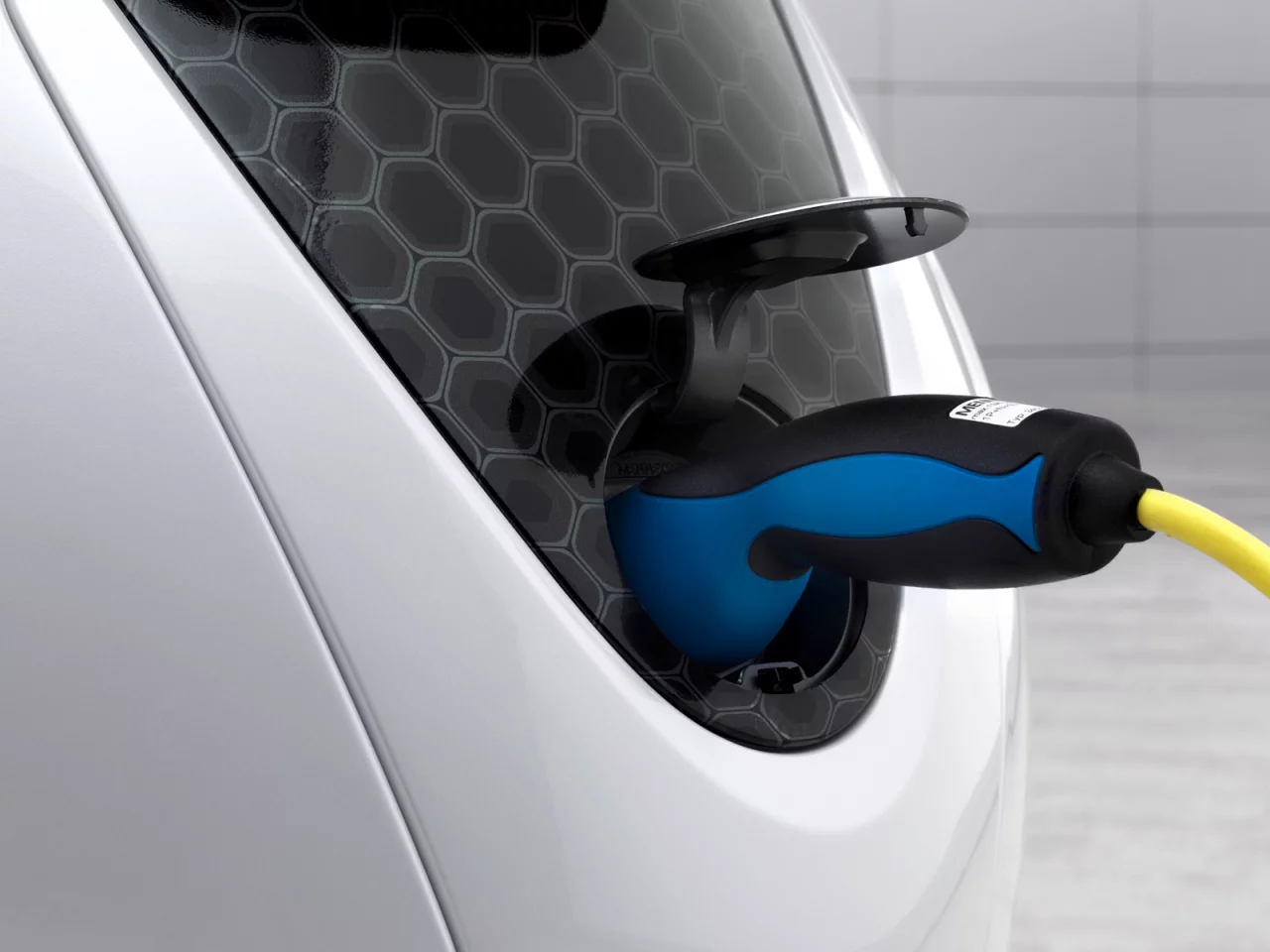 The charging socket of the smart escooter is stored at the front of the scooter underneath a hinged smart emblem