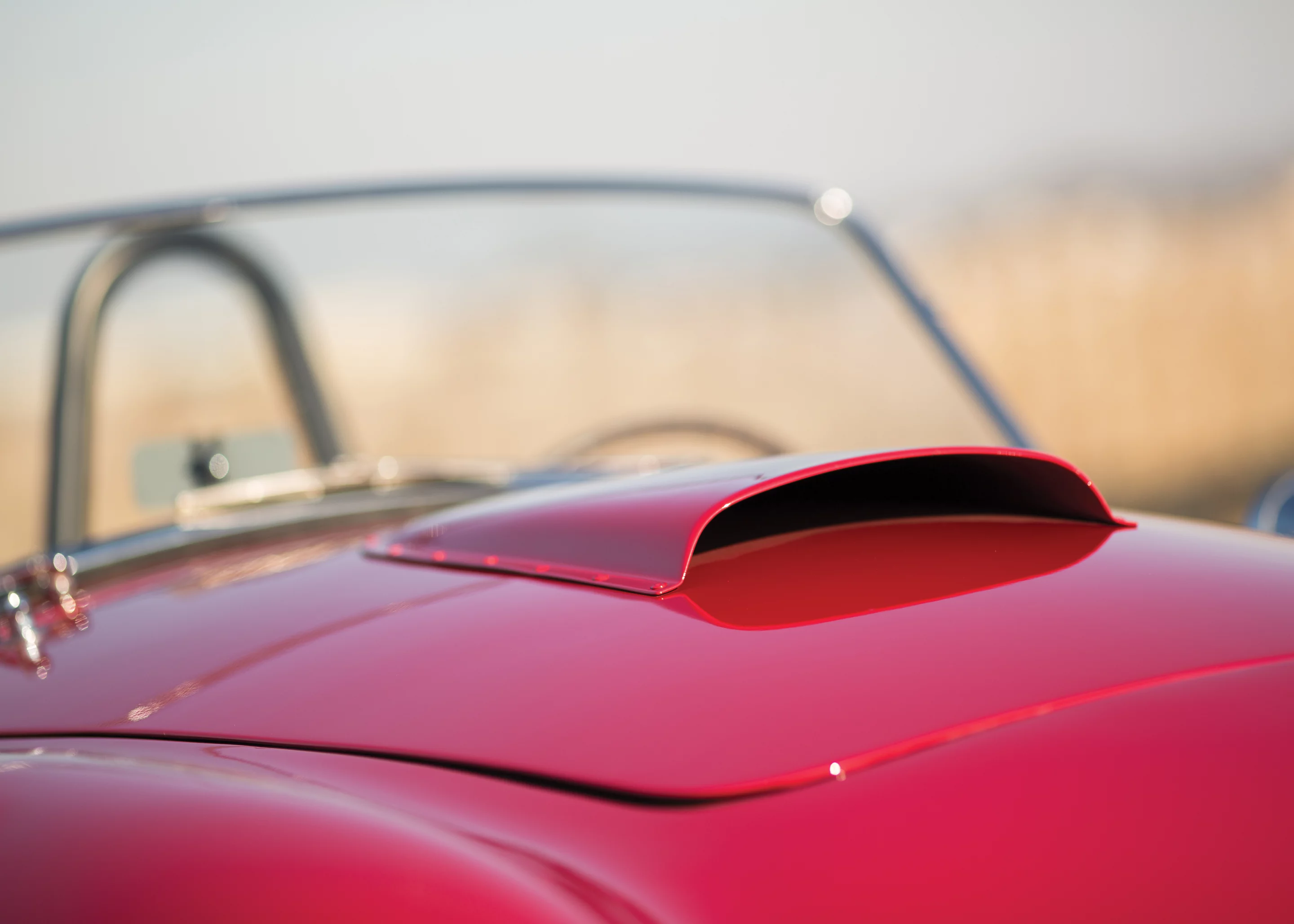 While much has been written about this Cobra, it is most famous for its appearances in promotional pieces for the menswear company, Mr. Formal Wear, the most famous of which depicts a buxom blonde, clad in white tuxedo shirt, bow tie, high heels, and nothing else, chatting on a payphone next to the Cobra before two astonished onlookers. Another piece, famously titled “Some Guys Have It Tough,” depicts the Cobra beachside, with its driver and his lovely passenger skinny-dipping in the distance. Those posters appeared on bedroom and workshop walls all over the country and became legend among Cobra enthusiasts. This is THAT car. It sold for $990,000.