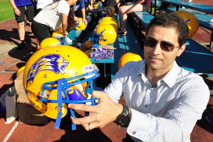 Postdoctoral fellow Daniel Abram – who is also CTO of spin-off company Shield-X – with a football helmet bearing a BrainShield decal (blue and white lion design)