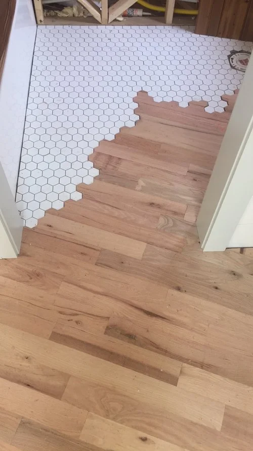 The Legacy tiny house's oak flooring continues into the bathroom, where it meets with honeycomb patterned tiling in a kinda-odd but certainly eye-catching transition