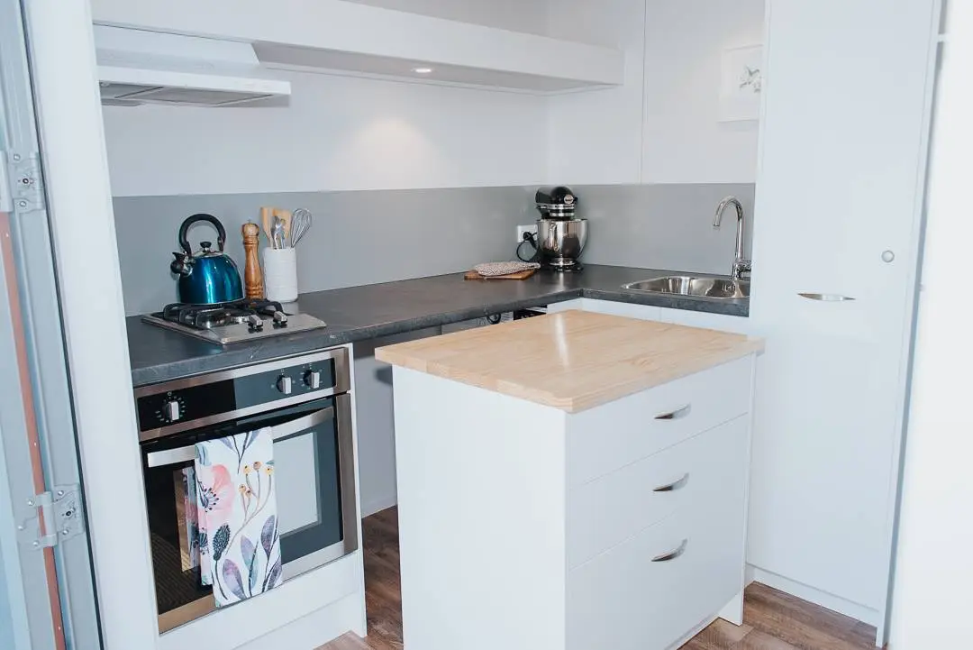 The Larissa and Tyler Tiny House's kitchen includes a pull-out cabinet that reveals a washing machine