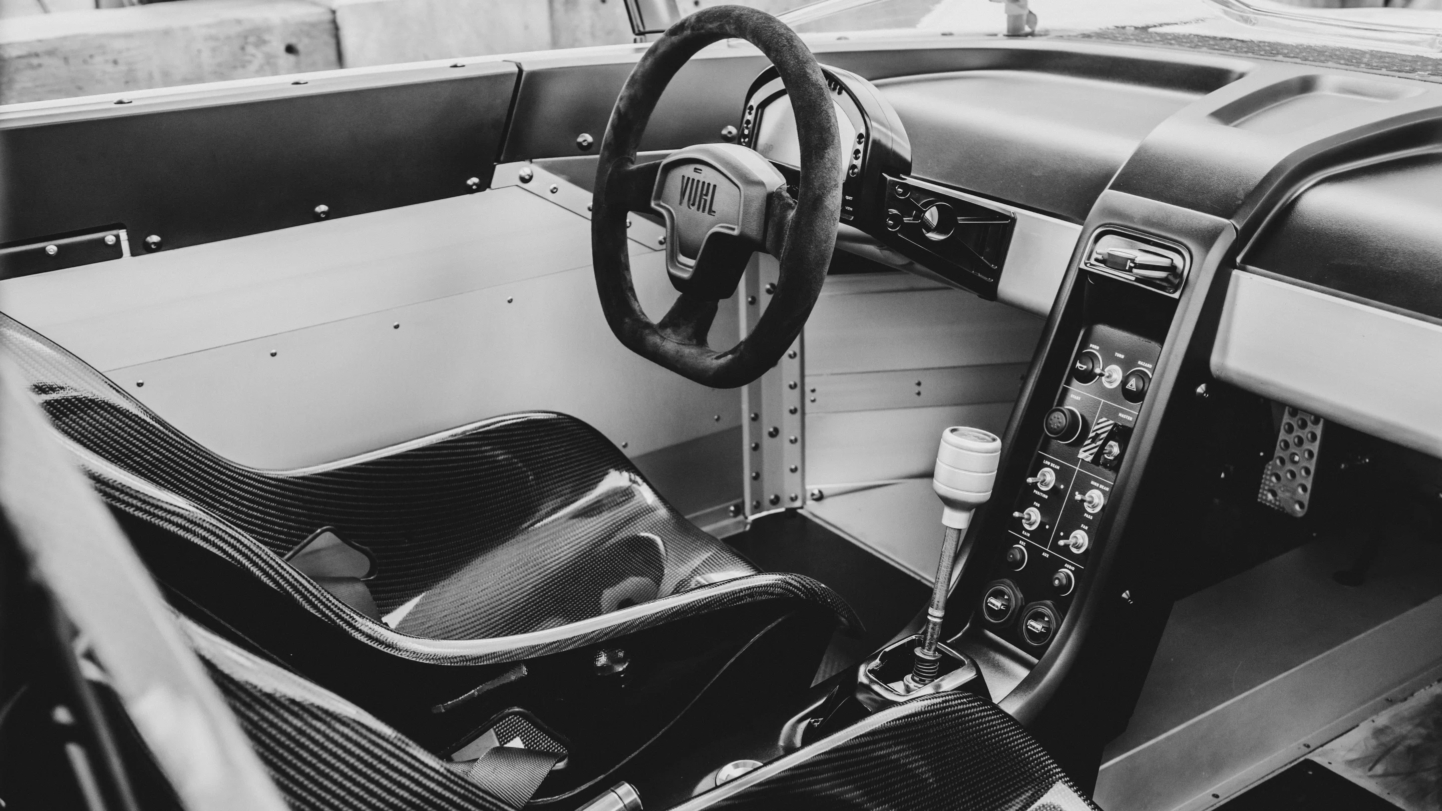 A 6-speed manual gearbox, waterproof suede, carbon fiber seats, minimalist interior and only the most essential switches and gauges make it to the cockpit