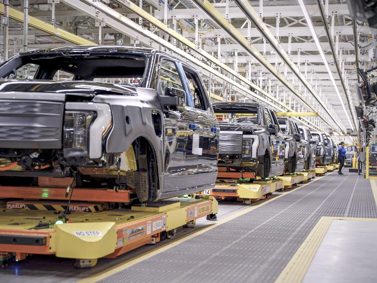 The Rouge Electric Vehicle Center is the first Ford plant without traditional in-floor conveyor lines, instead using robotic Autonomous Guided Vehicles to move F-150 Lightning trucks from workstation to station