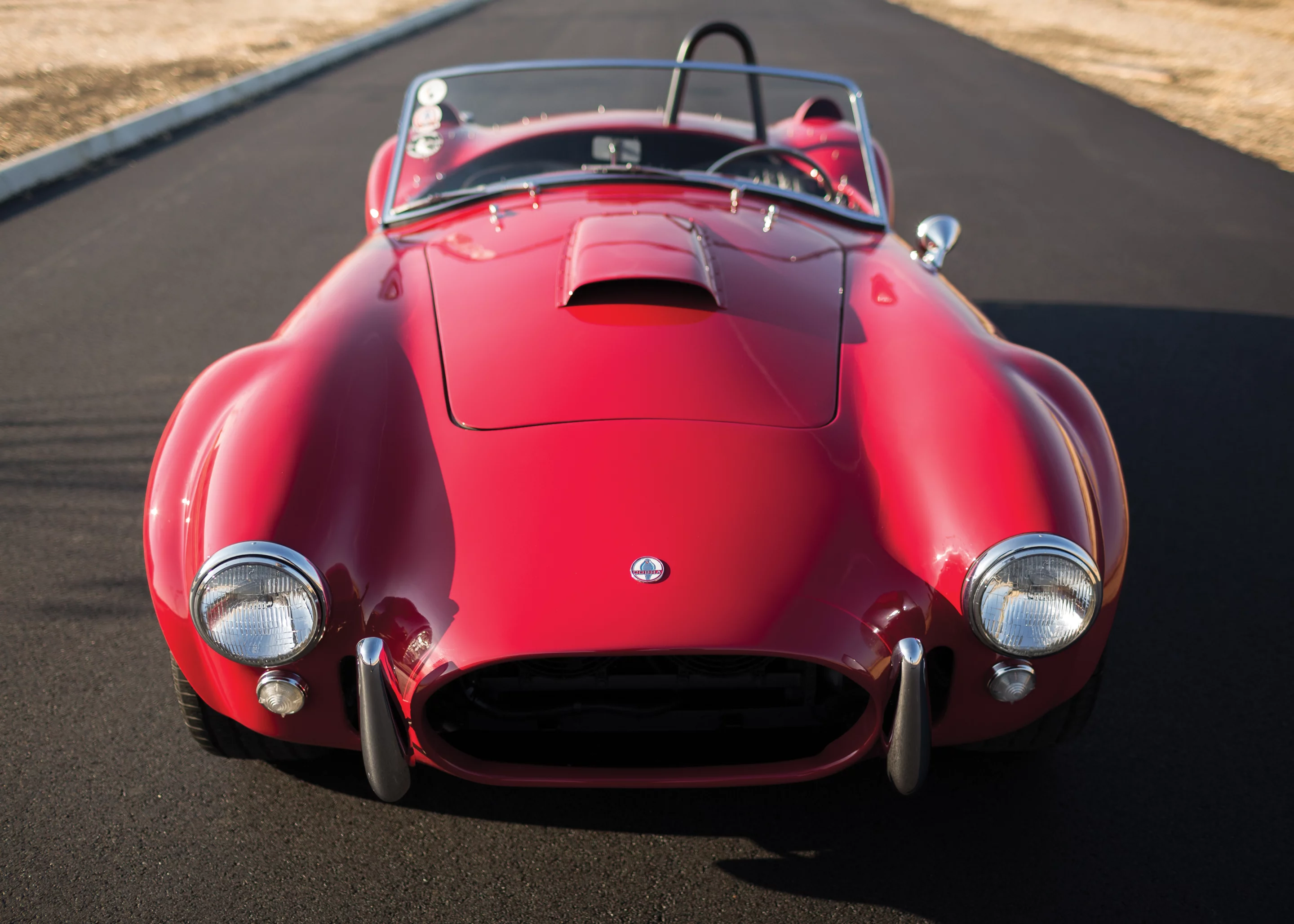 While much has been written about this Cobra, it is most famous for its appearances in promotional pieces for the menswear company, Mr. Formal Wear, the most famous of which depicts a buxom blonde, clad in white tuxedo shirt, bow tie, high heels, and nothing else, chatting on a payphone next to the Cobra before two astonished onlookers. Another piece, famously titled “Some Guys Have It Tough,” depicts the Cobra beachside, with its driver and his lovely passenger skinny-dipping in the distance. Those posters appeared on bedroom and workshop walls all over the country and became legend among Cobra enthusiasts. This is THAT car. It sold for $990,000.