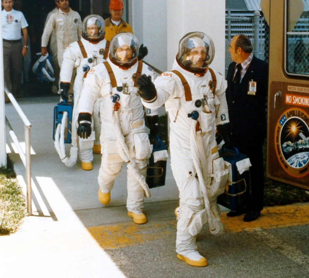Apollo astronauts carrying portable air conditioning units for their suits