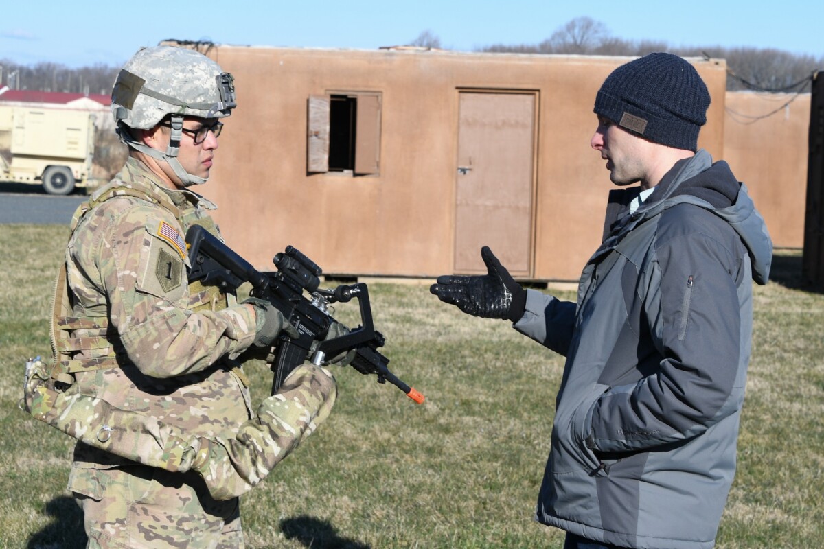 Army researcher Dan Baechle (right) briefs Sgt. Michael Zamora on how to use the Third Arm exoskeleton device