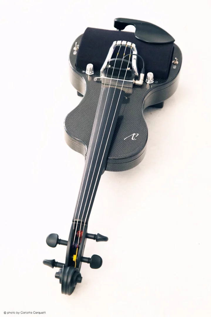 The instrument comprises a strong and rigid carbon fiber body, an aluminum tailpiece, a maple neck topped by an ebony fingerboard, maple pegbox and scroll, and ebony nut and pegs