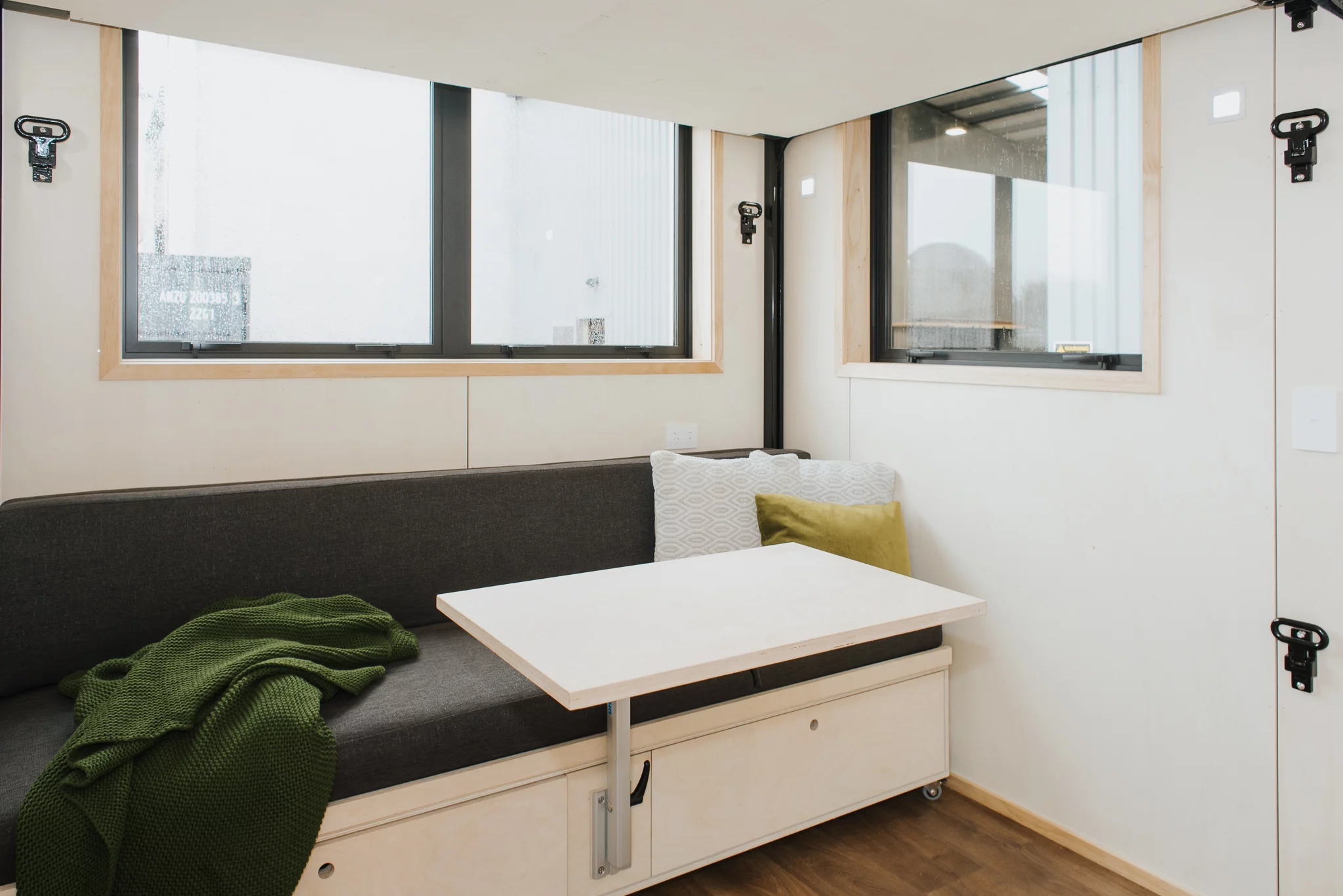 The Te Whare Nukunuku Tiny House's storage-integrated sofa features a removable table