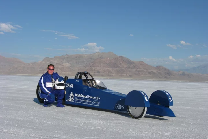 USU biochemist Michael R. Morgan posing beside the Aggie A-Salt Streamliner he piloted at Utah's Salt Flats (Photo: USU)