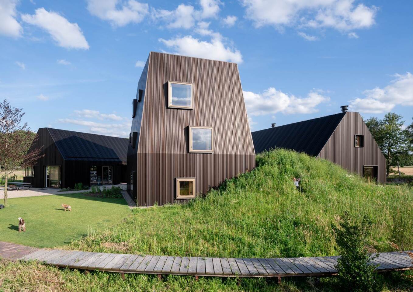 Two of the buildings are shaped similarly to traditional gabled barns, and the third structure is designed as a mini tower