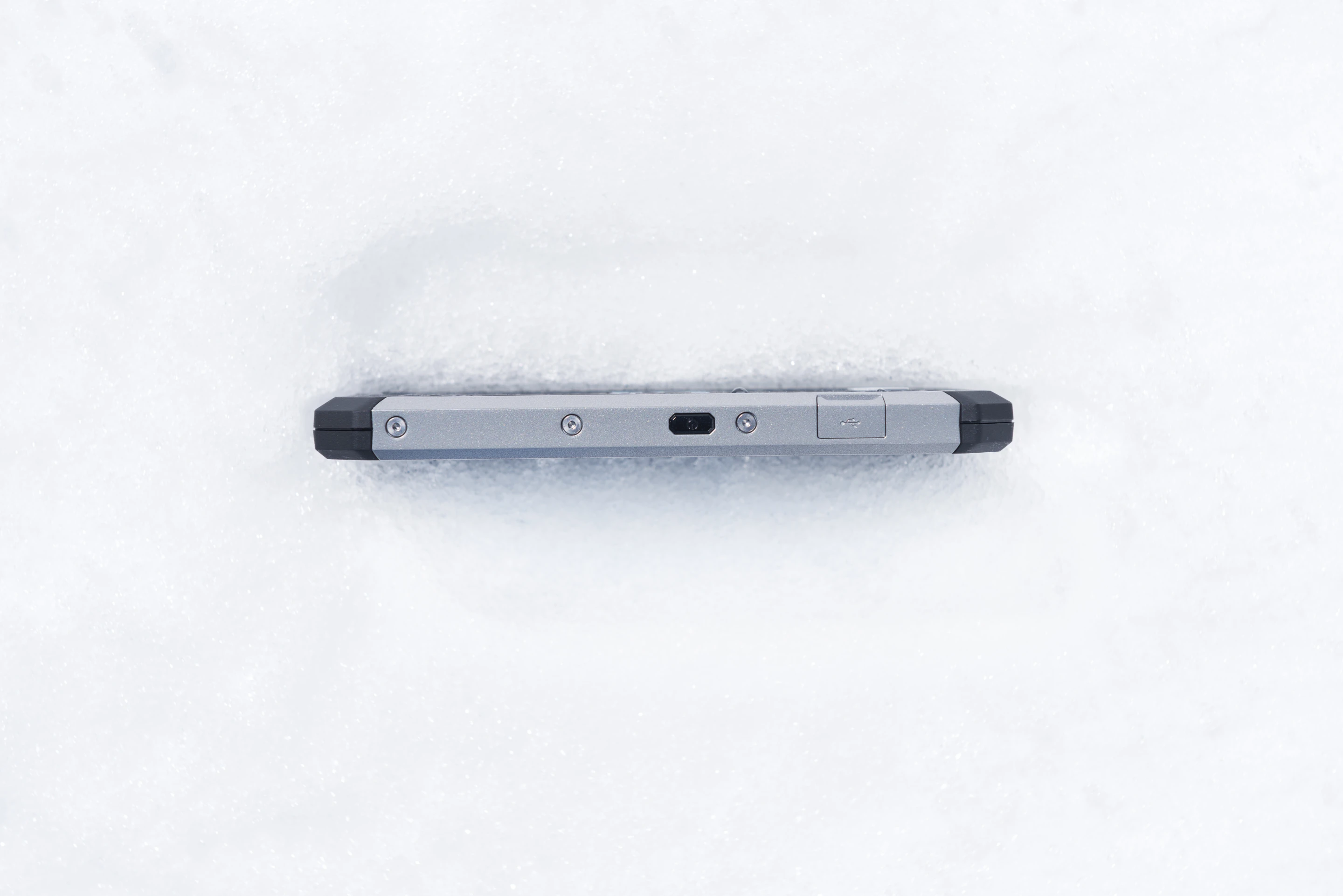 The Cat S50 smartphone stuck in the snow, seen in profile