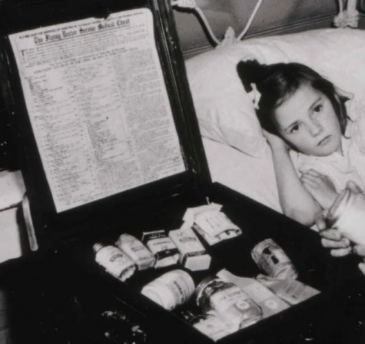 Blow-up of sick child image shows the official "Flying Doctor Service Medical Chest" in detail.