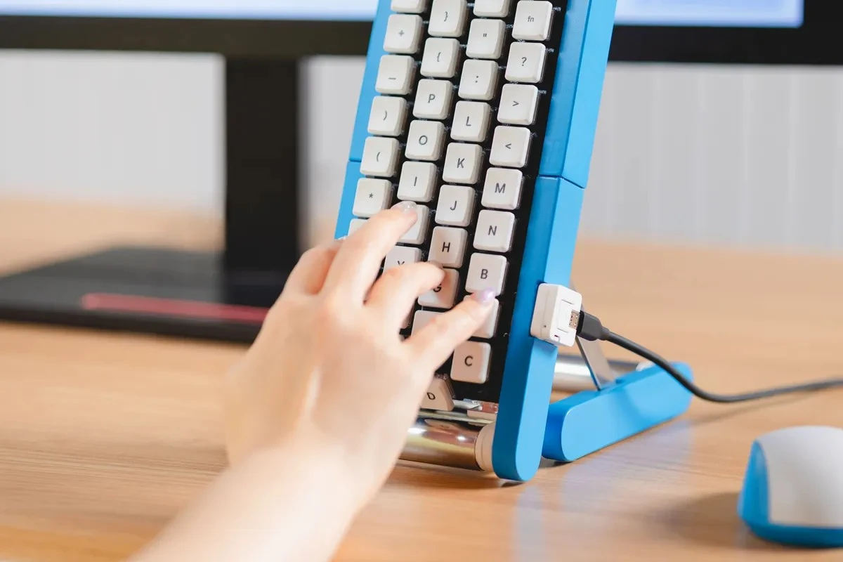 A typist taps a letter as it rolls into position on the motorized belt, enabling one-handed typing at a fixed hand location