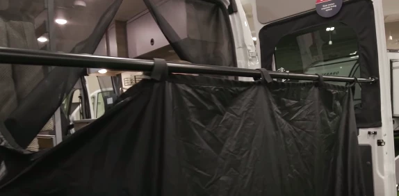 The multipurpose curtain hangs on the pole with Velcro loops, creating a rear change/shower room