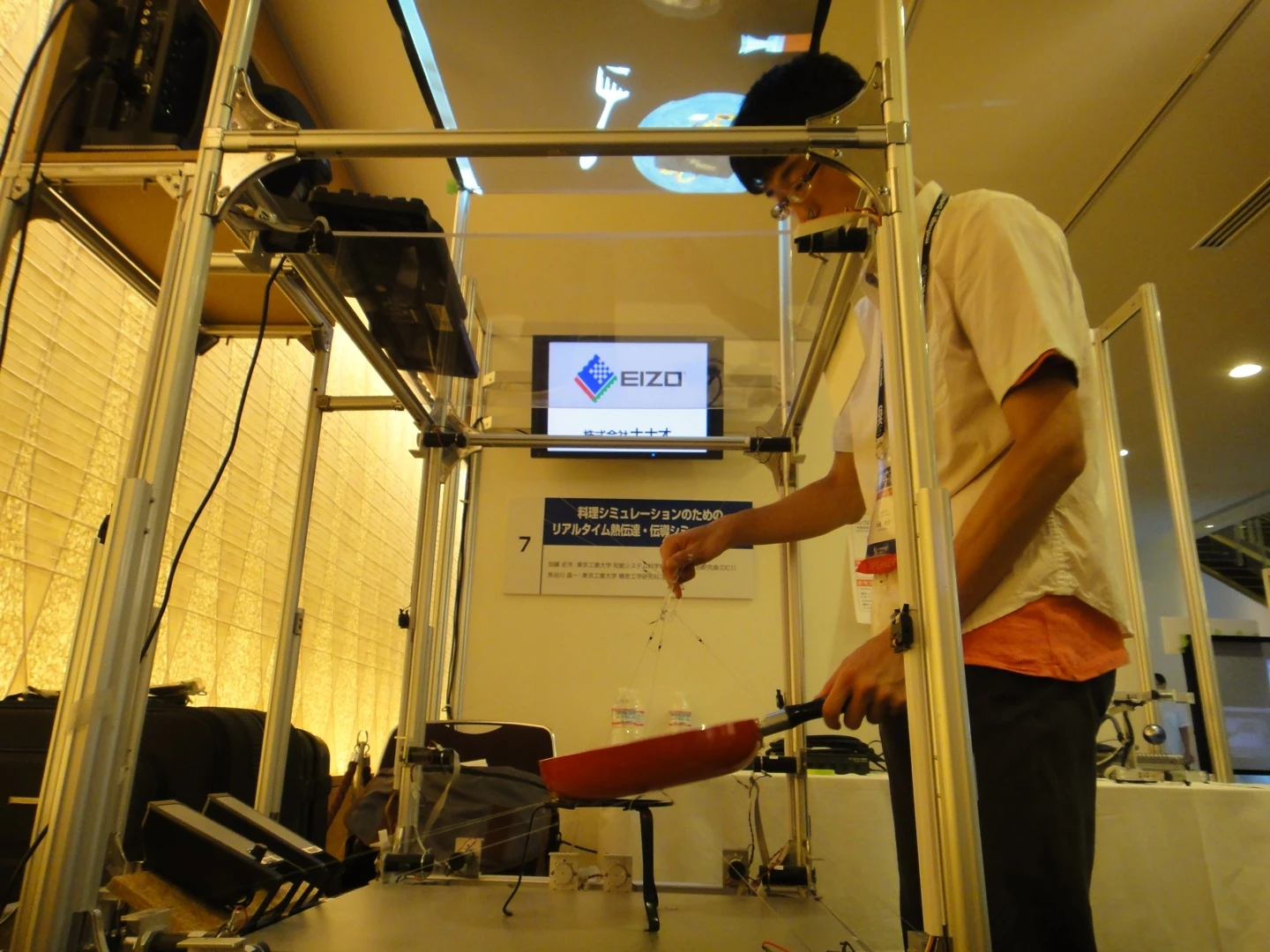 The cooking simulator uses a half-mirror display to show the virtual food in the pan