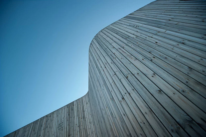 Unstained natural wooden panels stretch upwards from the ground.