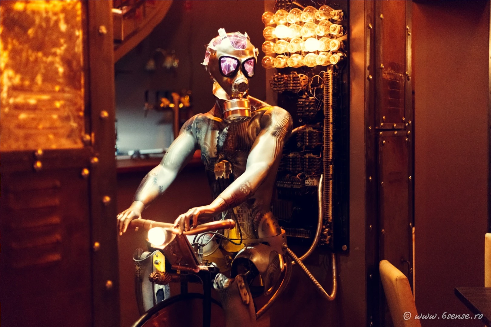 The "time slave" is a forlorn figure riding a bicycle, wearing a gas mask, and with a plasma globe in place of a brain