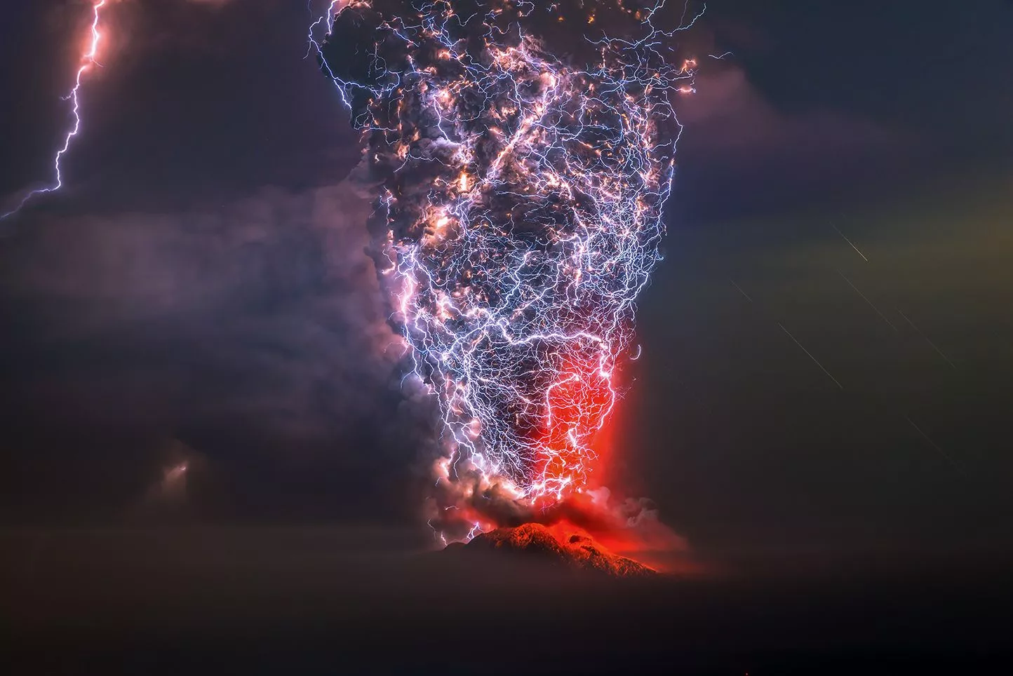 Winner in The Beauty of Nature. This photograph was taken during a violent night eruption of the Calbuco volcano in the Lagos region, Chile. An incredible dirt storm wraps the fumarole of the erupting volcano