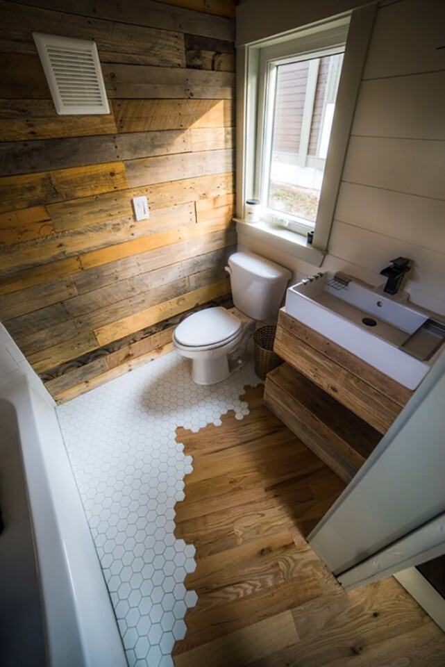 The Legacy tiny house's oak flooring continues into the bathroom, where it meets with honeycomb patterned tiling in a kinda-odd but certainly eye-catching transition