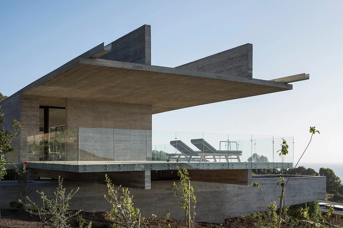 The pool at La Casa H can be accessed via the upper balcony and is housed inside a cantilevered concrete wedge that runs beneath the upper story and presents a sunken entranceway on the other side