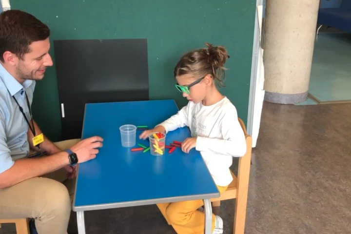 One of the patients can see well enough through her treated eye to sort crayons into cups