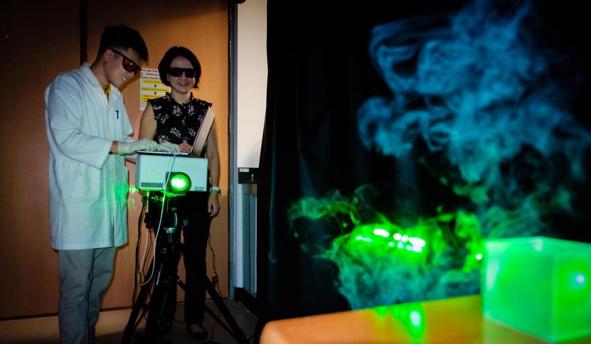 Assoc. Prof. Ling Xing Yi (right) with PhD student Phan Quang Gia Chuong, operating the gas analyzer laser device