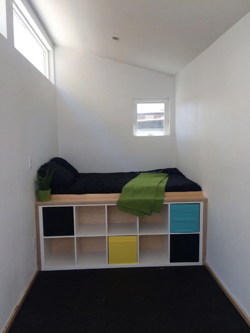 The interior includes a small cabinet and a bed with storage space underneath