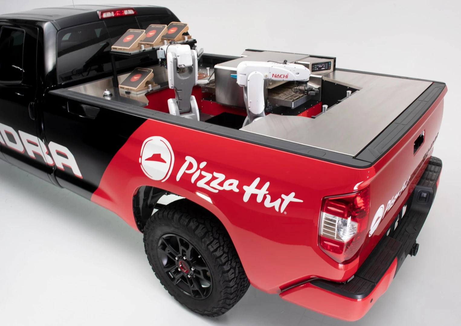 The Tundra Pie Pro's mobile pizza factory consists of two robotic arms, a refrigerator, and a high-intensity conveyor oven