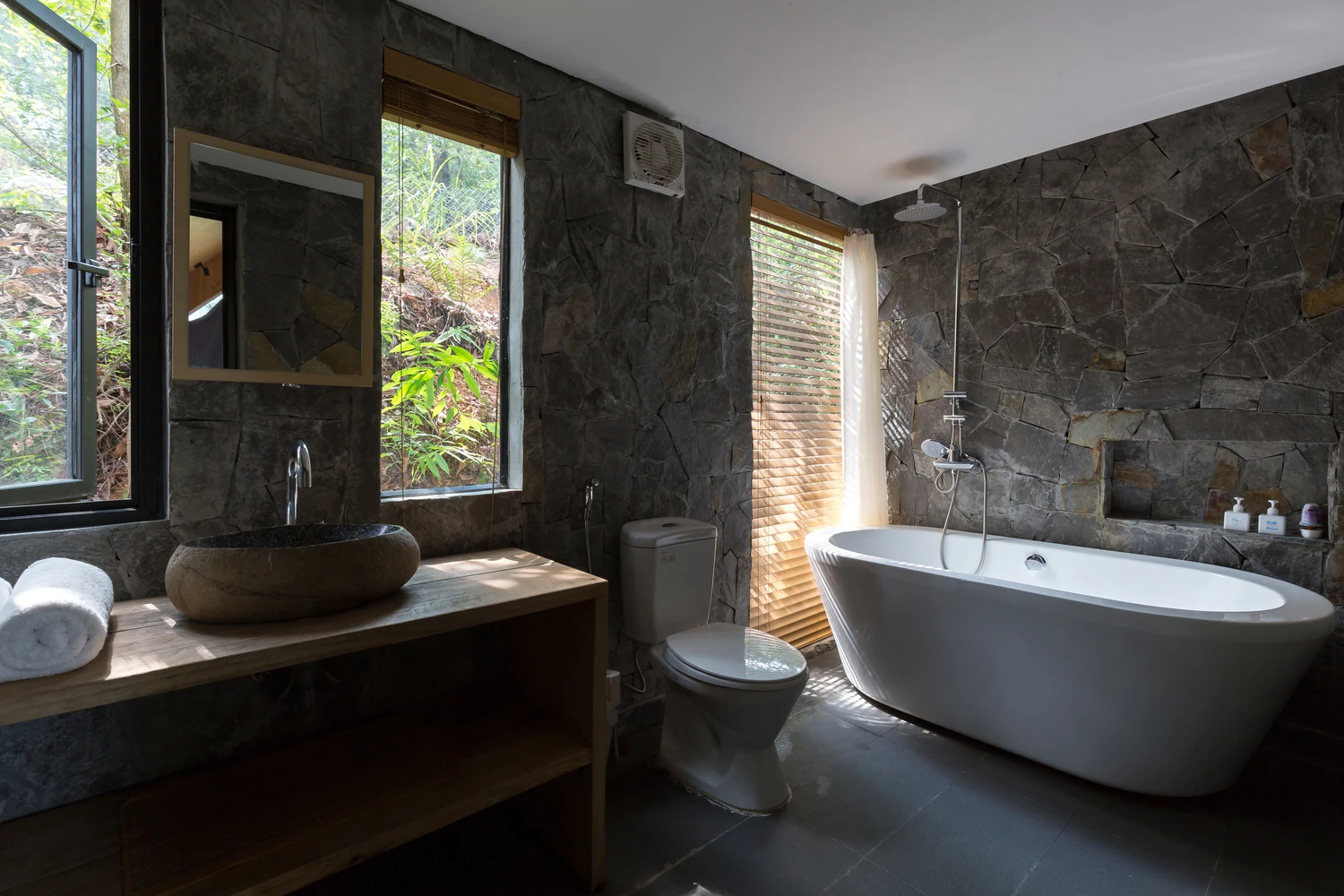 The bathroom features a free-standing bath and beautiful stone walls