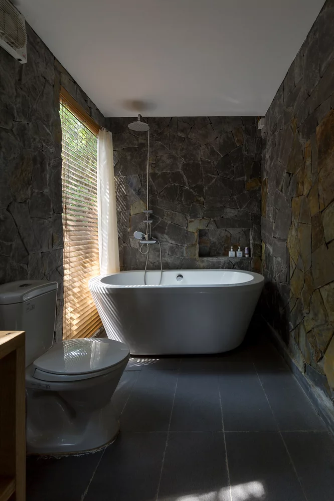 The gorgeous Forest House 02 bathroom with stone walls and natural light