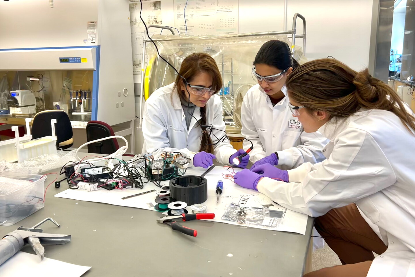 Leila Alidokht (left) and Mariana Lanzarini-Lopes (right) work on the UV-emitting glass with graduate research assistant Athira Haridas (center)