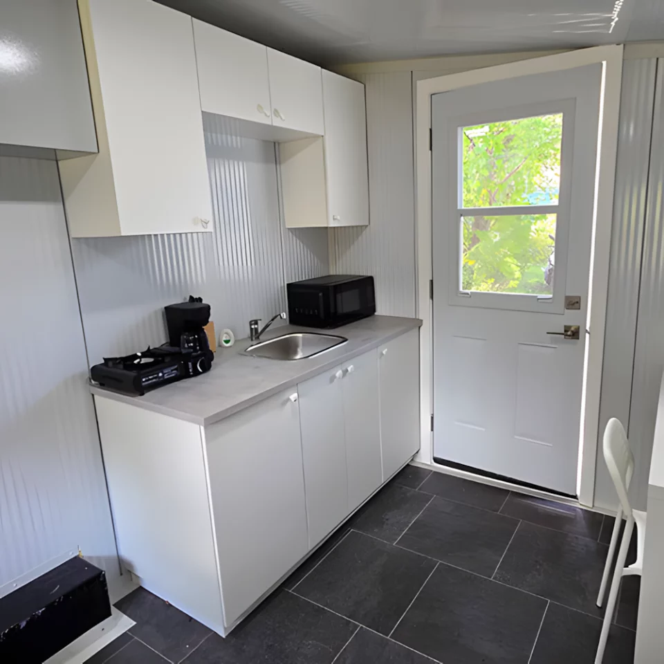 The larger tiny house includes a kitchenette and a desk area